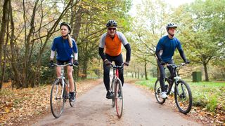 Woman and two men cycling through park