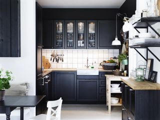 small black kitchen with base and wall cabinets and freestanding wooden unit