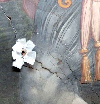 A tiny hole was created after a loose fragment of paint from the Vasari mural was removed by restorers and the surrounding area was secured. The point of entry was located at an existing crack in the Vasari mural.