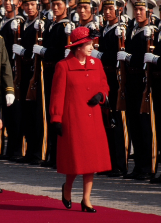 Chinese President Li Xiannian (1909 - 1992) (fore, left) and British monarch Queen Elizabeth II (1926 - 2022) (fore right, in red) walk together during a welcoming ceremony for the latter's Royal Visit, Beijing, China