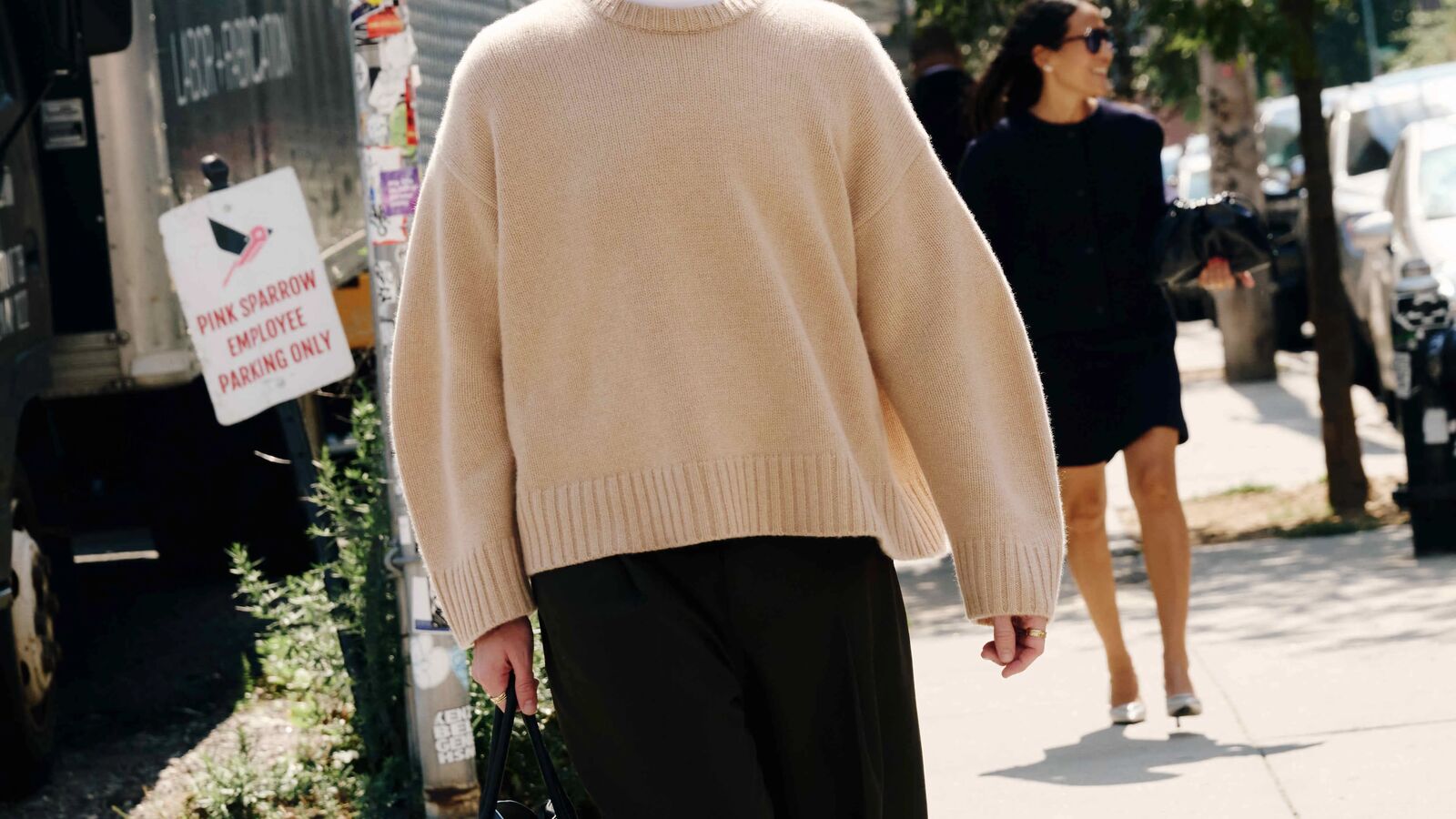 Person walking down the street and wearing a baggy crewneck sweater.