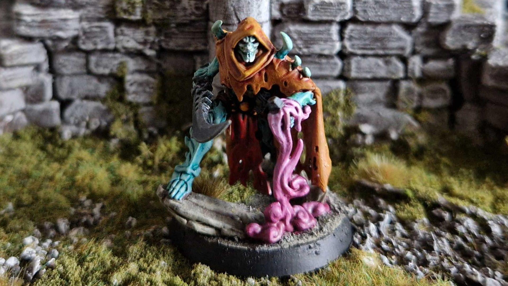 A hooded skeletal figure on a grassy, ruined background