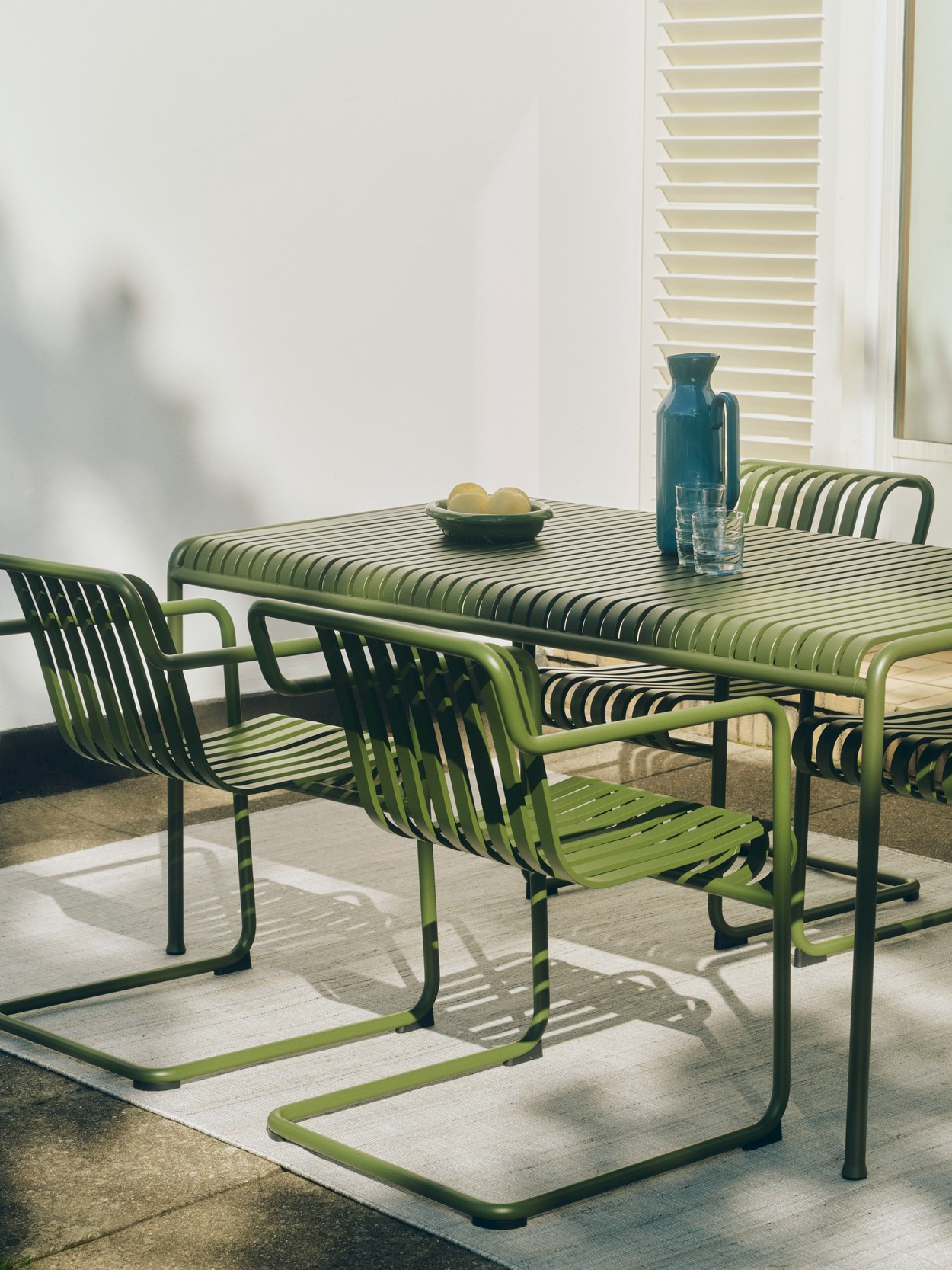 HAY Palissade green cantilever chairs and dining table in green in sunny courtyard dining area