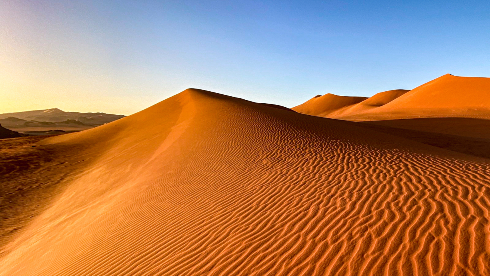 A photo of an orange sand dune with a defined point