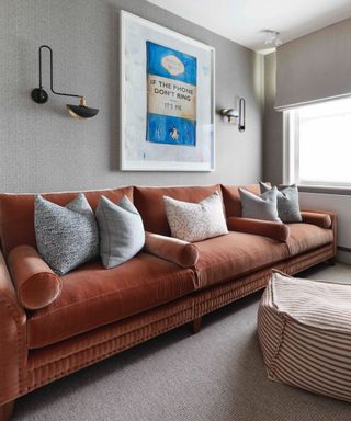 neutral living room with burnt orange sofa, patterned cushions, striped beanbag and artwork