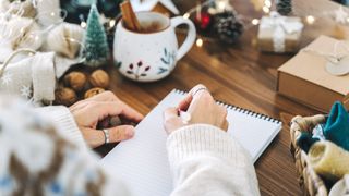 Woman hand holding pen on notepad at home on winter holidays xmas