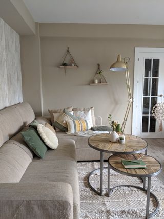 A greige living room by Cult furniture with upholstered sofa, assortment of cushions, wood and metal coffee table and metallic gold floor lamp