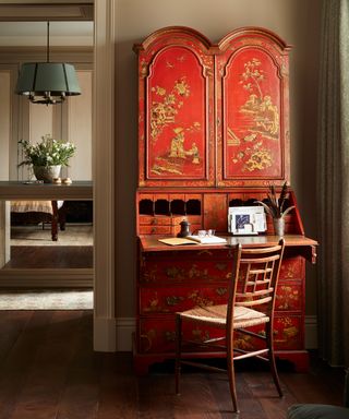 Oriental style red desk and oriental style chair in room with neutral walls and wood floor