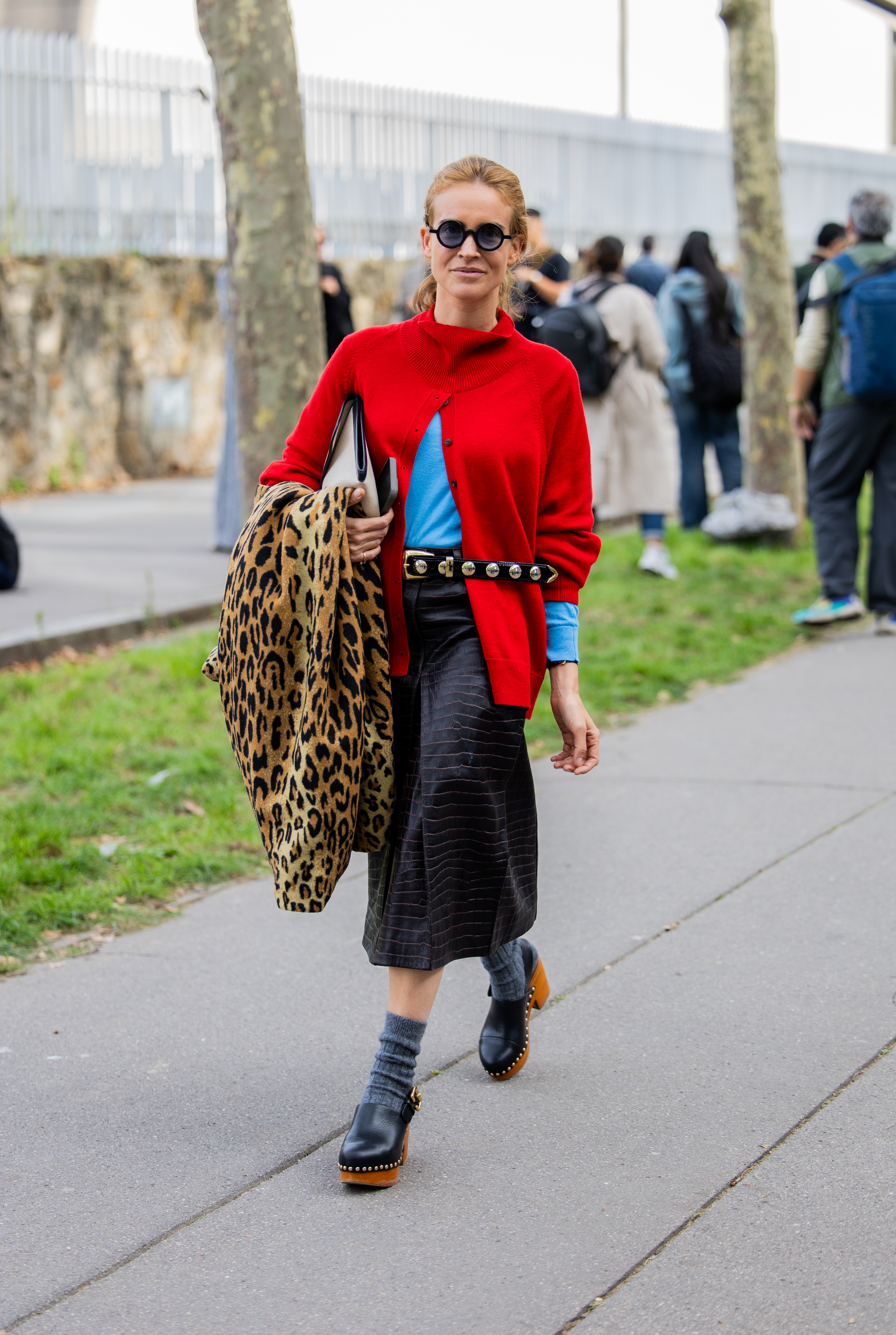 Blanca Miro wearing a red cardigan and brown skirt
