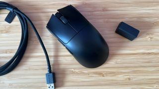 Razer Viper V3 Pro gaming mouse with cable and HyperPolling dongle on a wooden desk