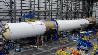 a huge white rocket sits on its side in a hangar