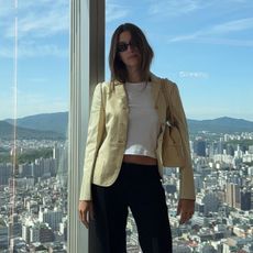 Hailey Bieber wearing a white T-shirt, a tan blazer, cropped black pants, and heeled Massimo Dutti wegde thong sandals.