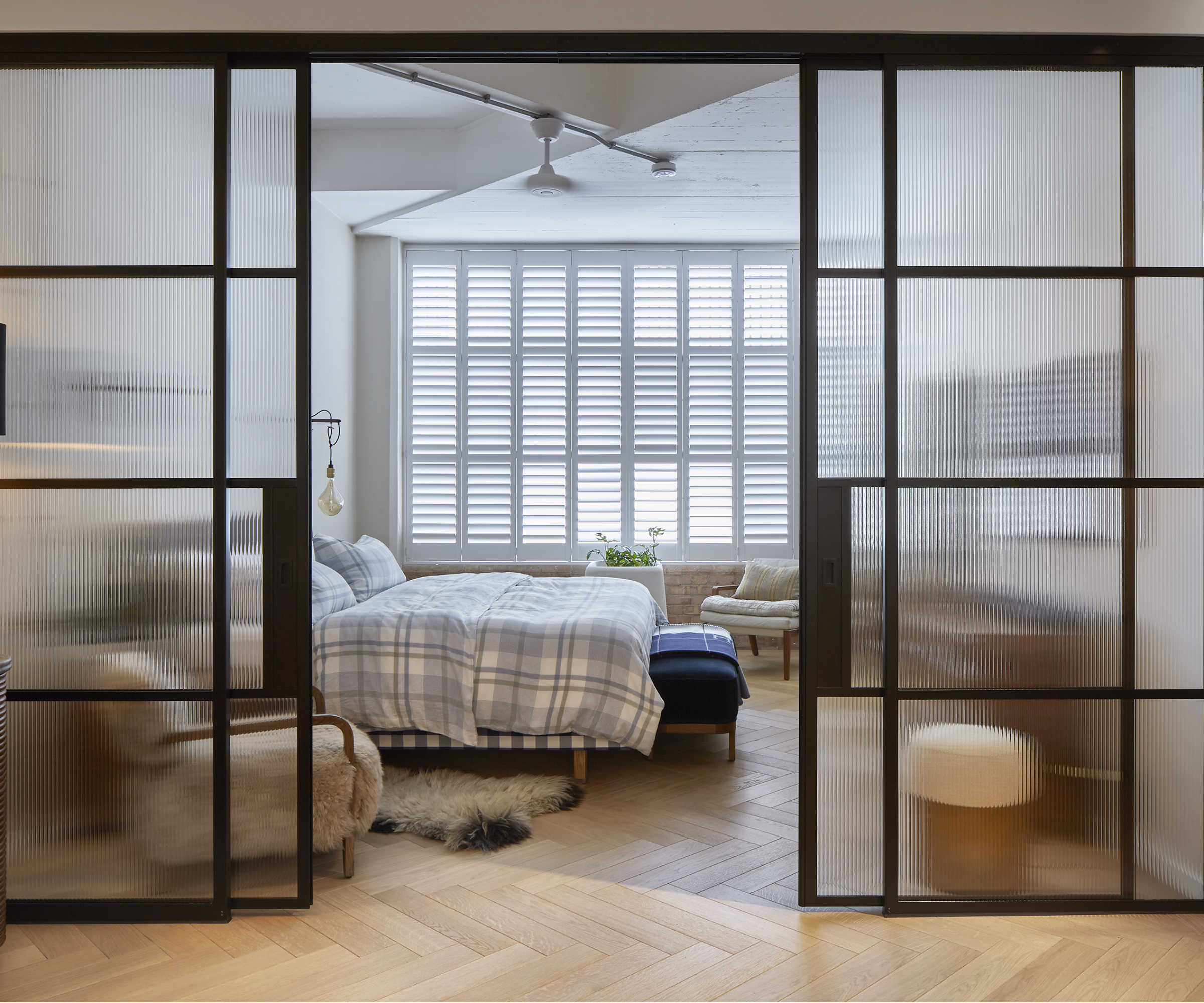 bedroom with crittal sliding doors and level wooden flooring throughout