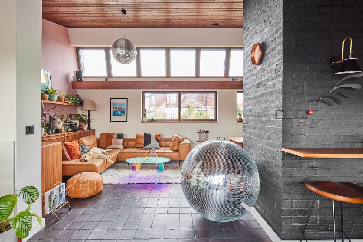 A modernist living room with a large disco ball and an l-shaped leather sofa with a Labrador sleeping on it