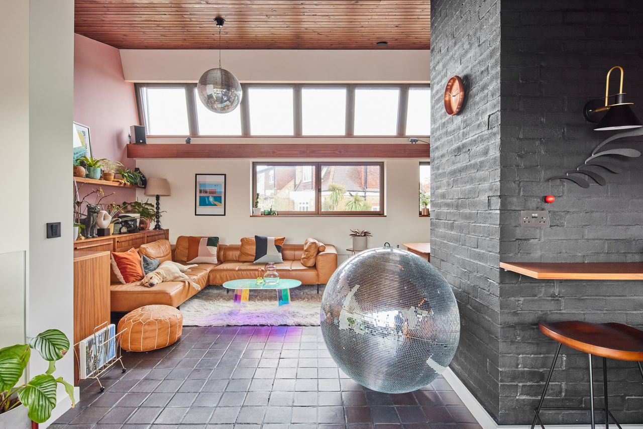 A modernist living room with a large disco ball and an l-shaped leather sofa with a Labrador sleeping on it