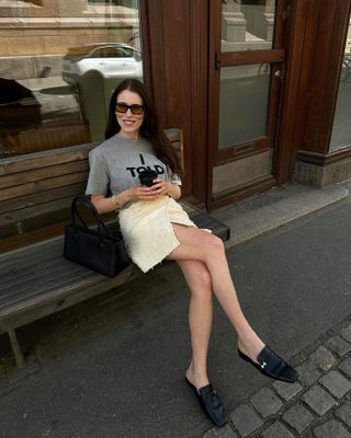 Woman wearing a gray T-shirt, miniskirt, and loafers.