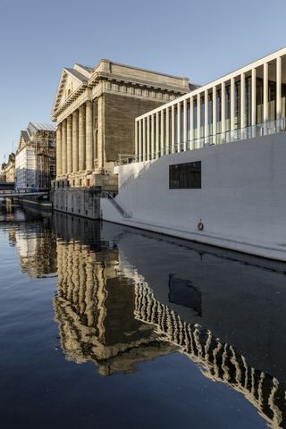 A side-on view of the building alongside other museum buildings that sit on the river.