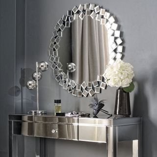 mirror on grey wall with stainless steel cabinet and rose flower in vase