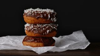 Three chocolate donuts stacked one on top of the other