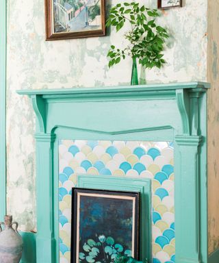 teal fireplace with patterned tiles, faded patterned wallpaper and vase of foliage