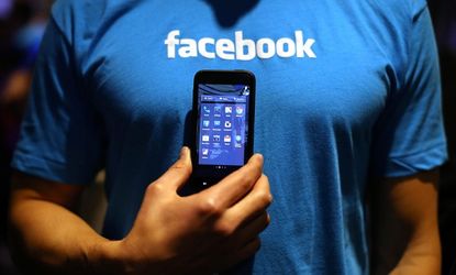 A Facebook employee holds a phone that is running the new "Home" program on April 4.