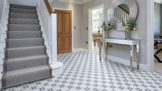 large hallway with white staircase with stair runner and patterned tiled floor
