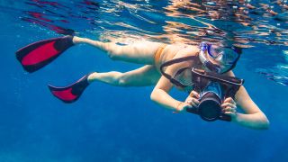 Woman snorkelling with camera in underwater housing
