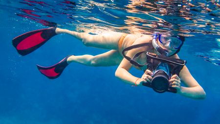 Woman snorkelling with camera in underwater housing