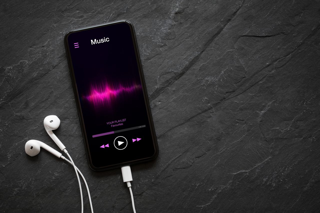 A phone with earphones on a table playing music