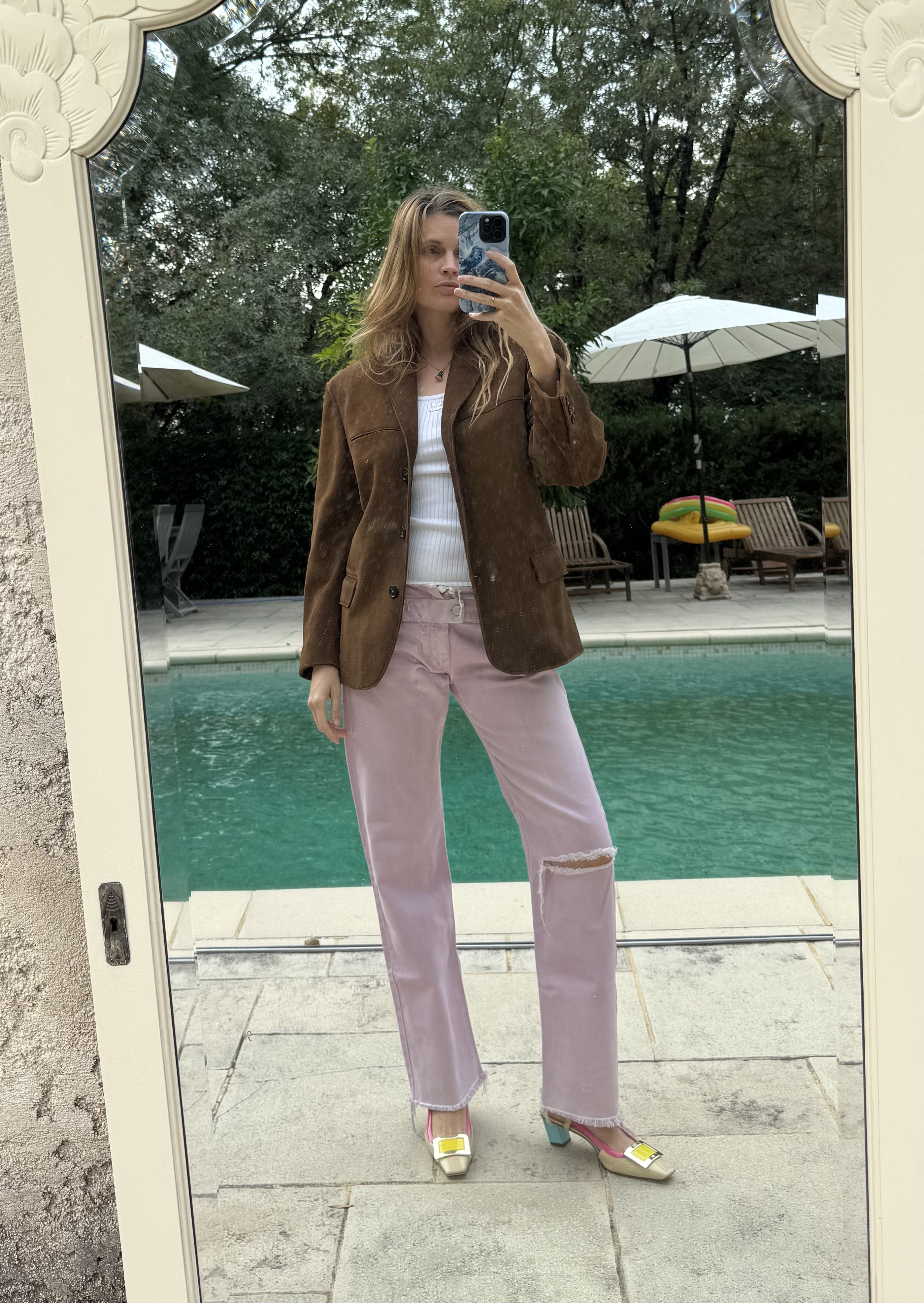 French writer and editor Eug&amp;eacute;nie Trochu poses in a brown suede jacket, white top, pink distressed jeans, and colorful heels