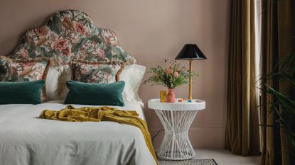 a dusty pink bedroom with a patterned headboard