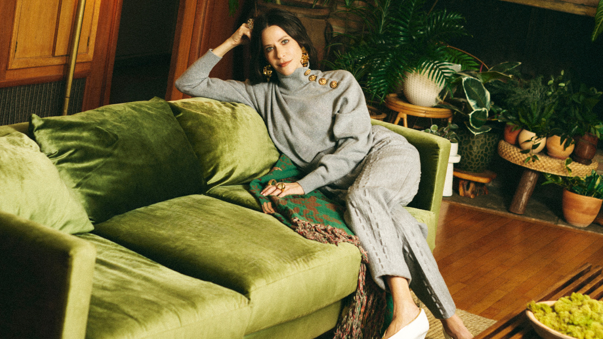Jackie Tohn forBest Knockoff Luxury Clothing
's Portrait Sessions feature. She is sitting on a green velvet couch wearing a gray sweater and matching trousers.