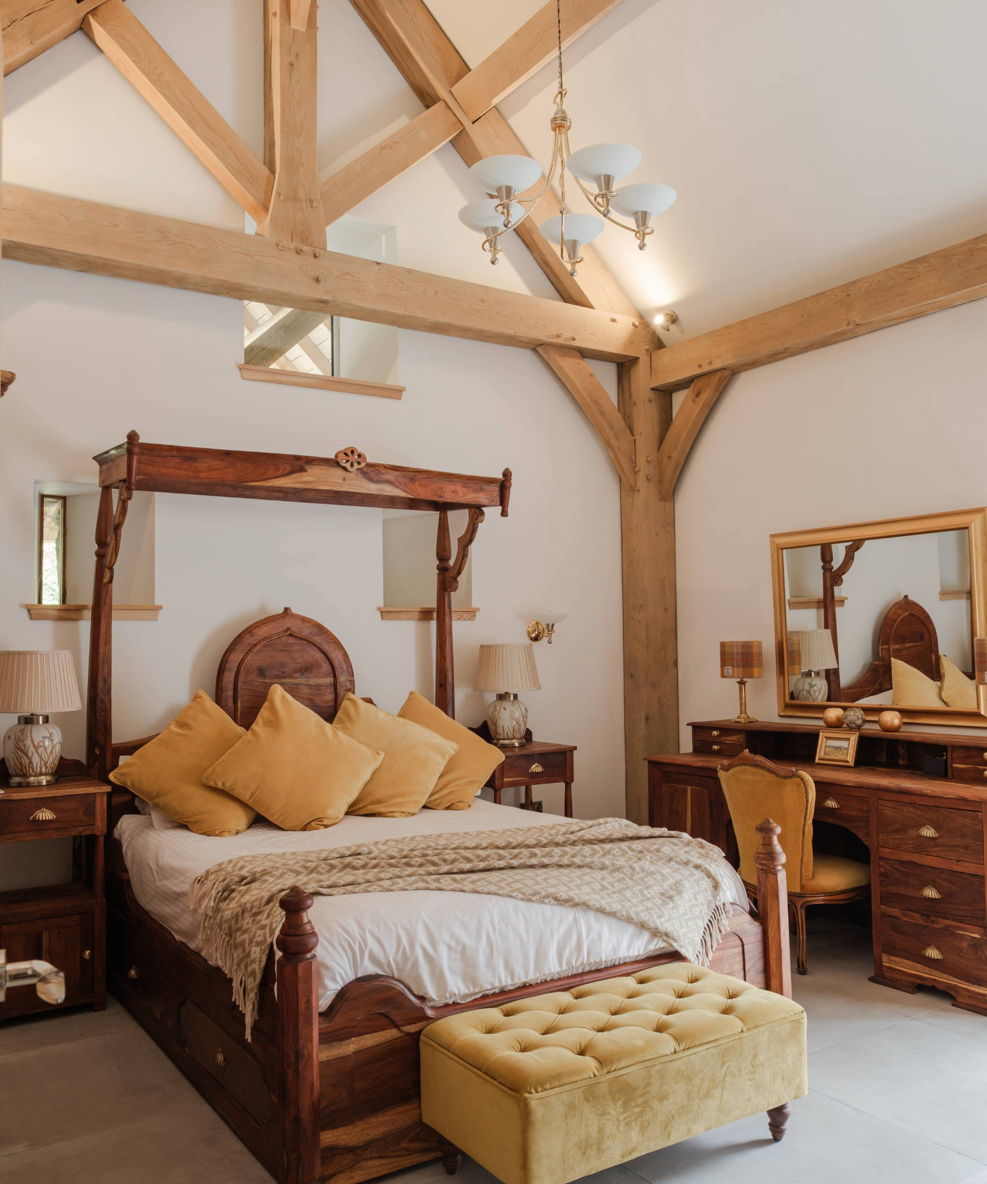 Bedroom with four poster bed, dresser, and ottoman