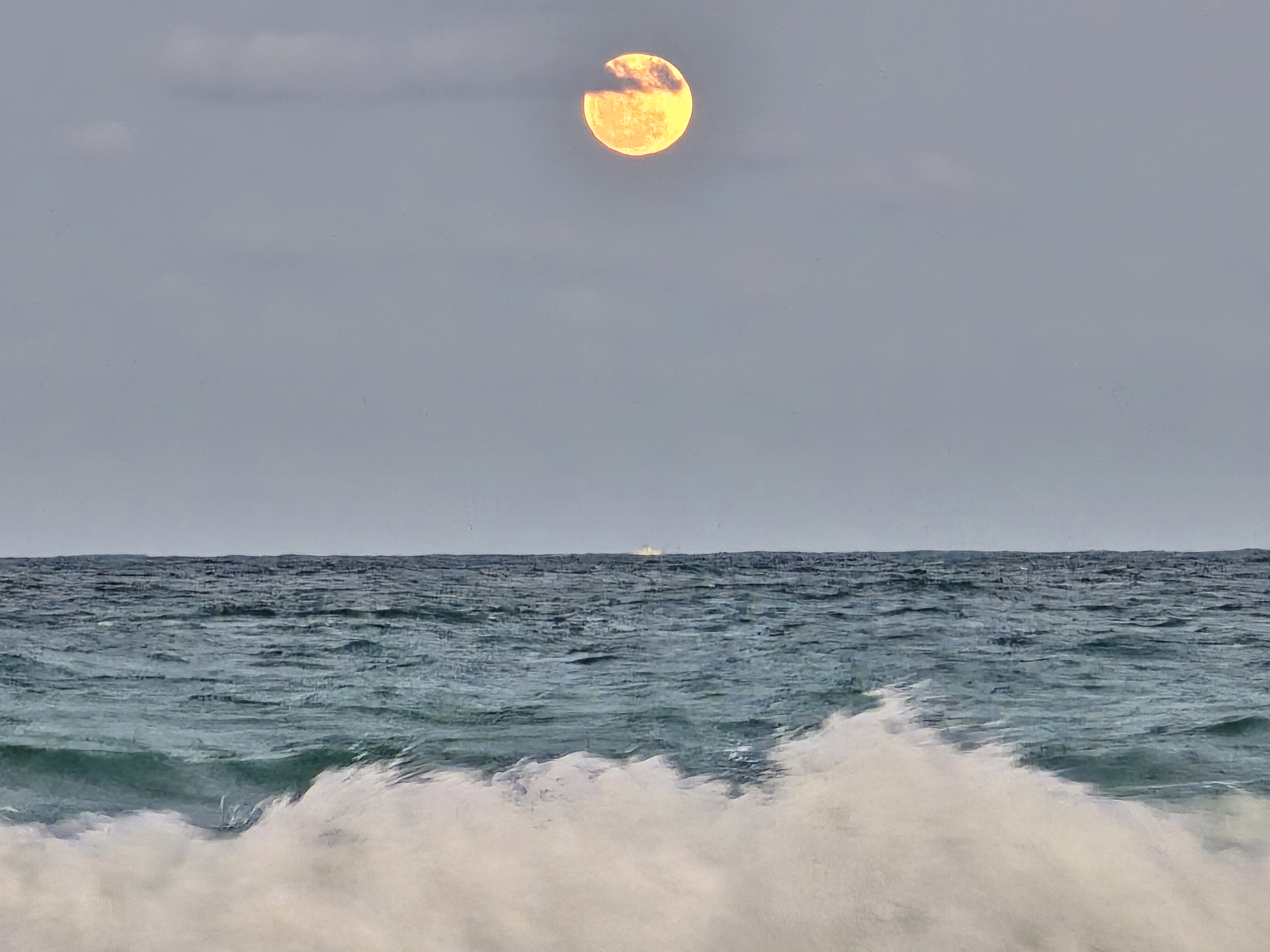 the full moon above an ocean shoreline
