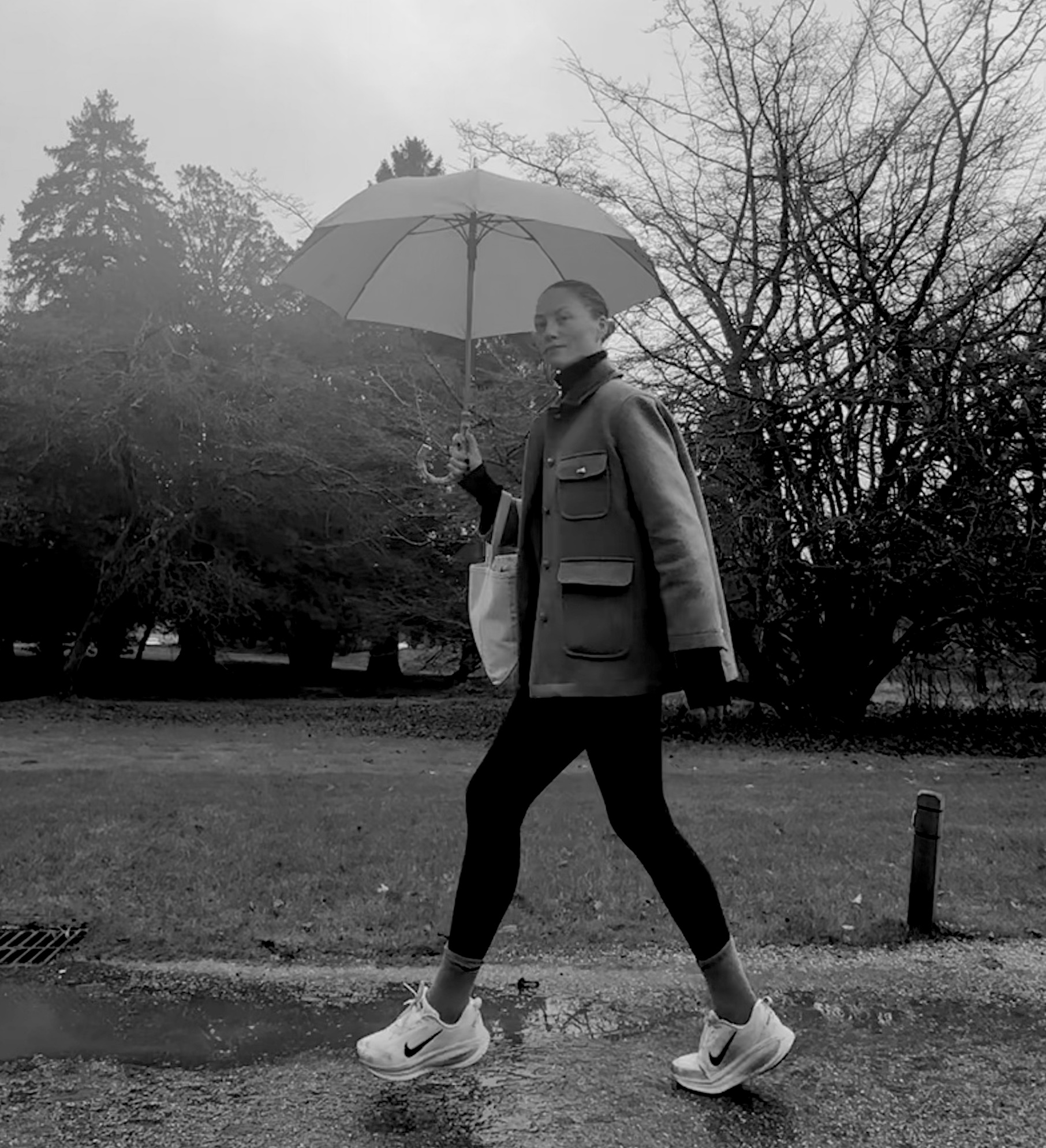 Brooke Ely Danielson wearing sneakers, leggings, and an umbrella with her turtleneck