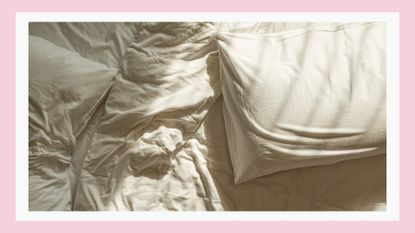 A picture of wrinkled white sheets and two pillows on a bed / in a pink template