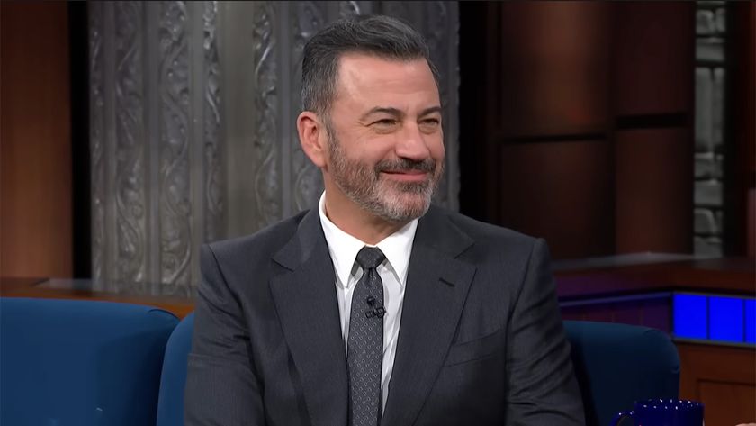 Jimmy Kimmel is wearing a suit and smiles as he cracks a joke on The Late Show. 