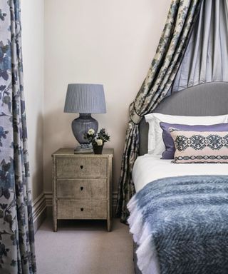 Bedroom with double bed below fabric canopy, blue and white bedding and grey carpet