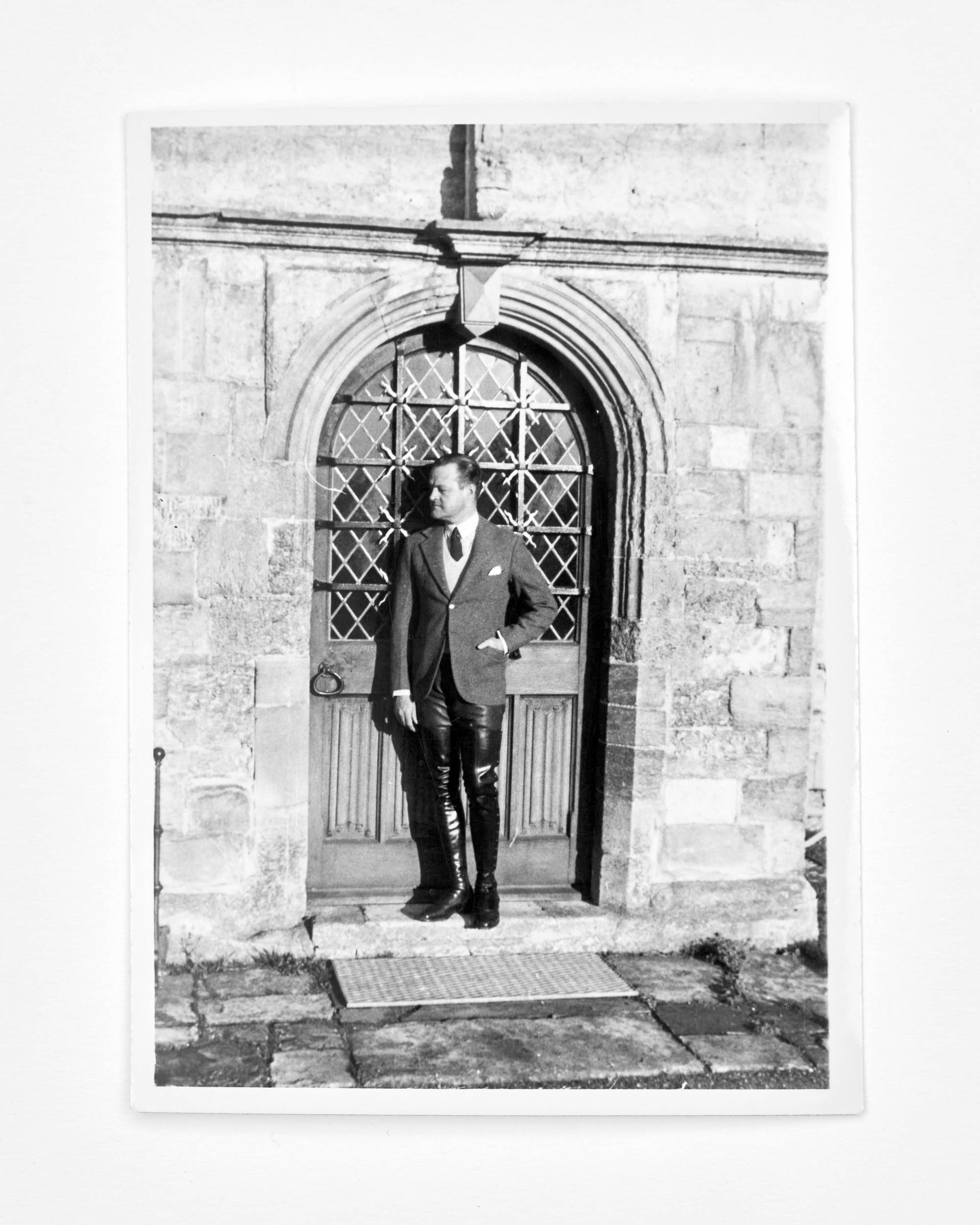 BW photo of man standing by intricate door
