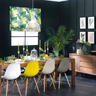 Dark green and black dining room with wooden furniture, houseplants and botanical window blind