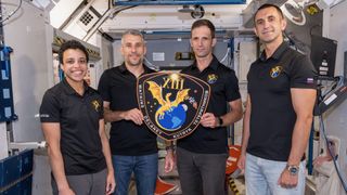 The four members of NASA’s SpaceX Crew-13 mission to the International Space Station display their mission plaque inside a training mockup of a space station module. From left: Commander Jessica Watkins and Pilot Luke Delaney, both from NASA, and Mission Specialists Joshua Kutryk of the Canadian Space Agency and Sergey Teteryatnikov of Roscosmos.