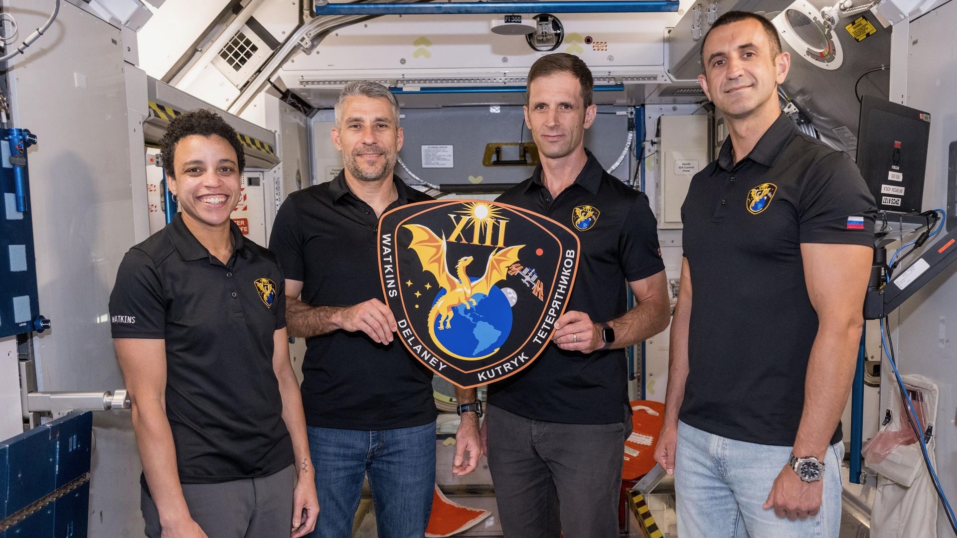The four members of NASA&rsquo;s SpaceX Crew-13 mission to the International Space Station display their mission plaque inside a training mockup of a space station module. From left: Commander Jessica Watkins and Pilot Luke Delaney, both from NASA, and Mission Specialists Joshua Kutryk of the Canadian Space Agency and Sergey Teteryatnikov of Roscosmos.