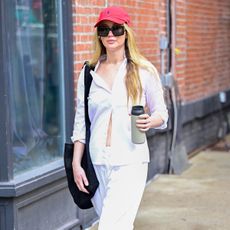 Jennifer Lawrence wearing a white shirt and red Polo baseball cap