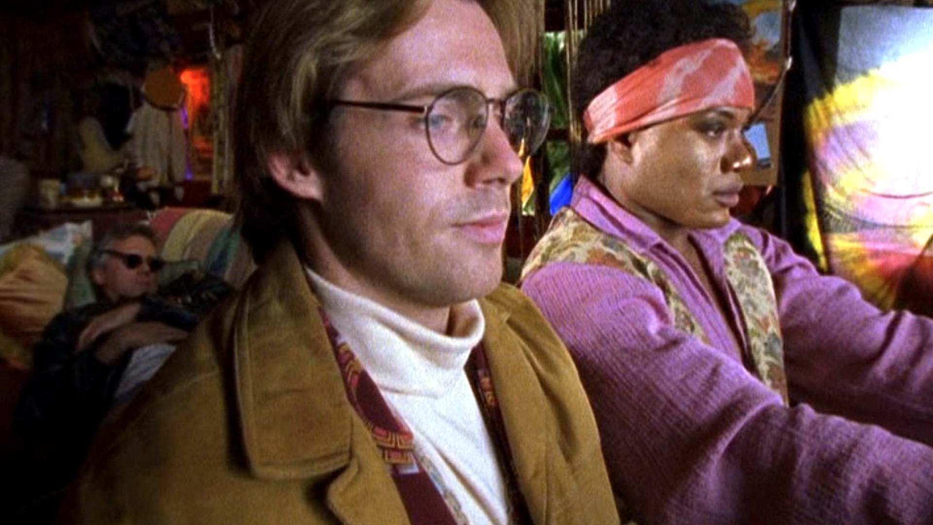 Screenshot from Stargate SG-1 showing two men dressed in 1960's groovy attire.