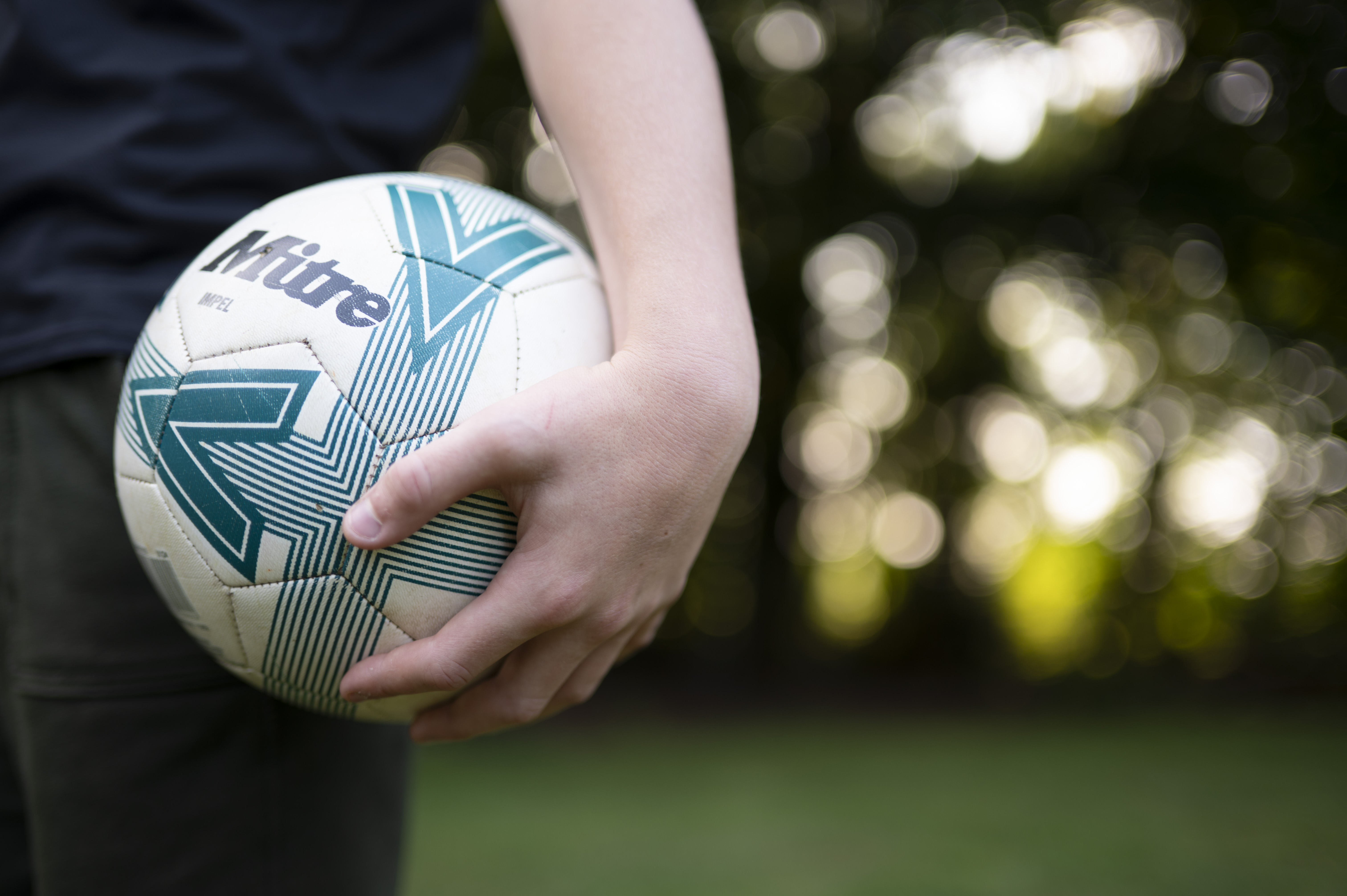 Footballer holding a football, closeup, taken with the Nikon Z 35mm f/1.4 lens