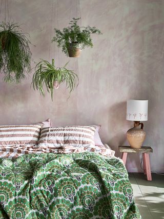 House plants hanging in a peachy boho bedroom with pink and green accents