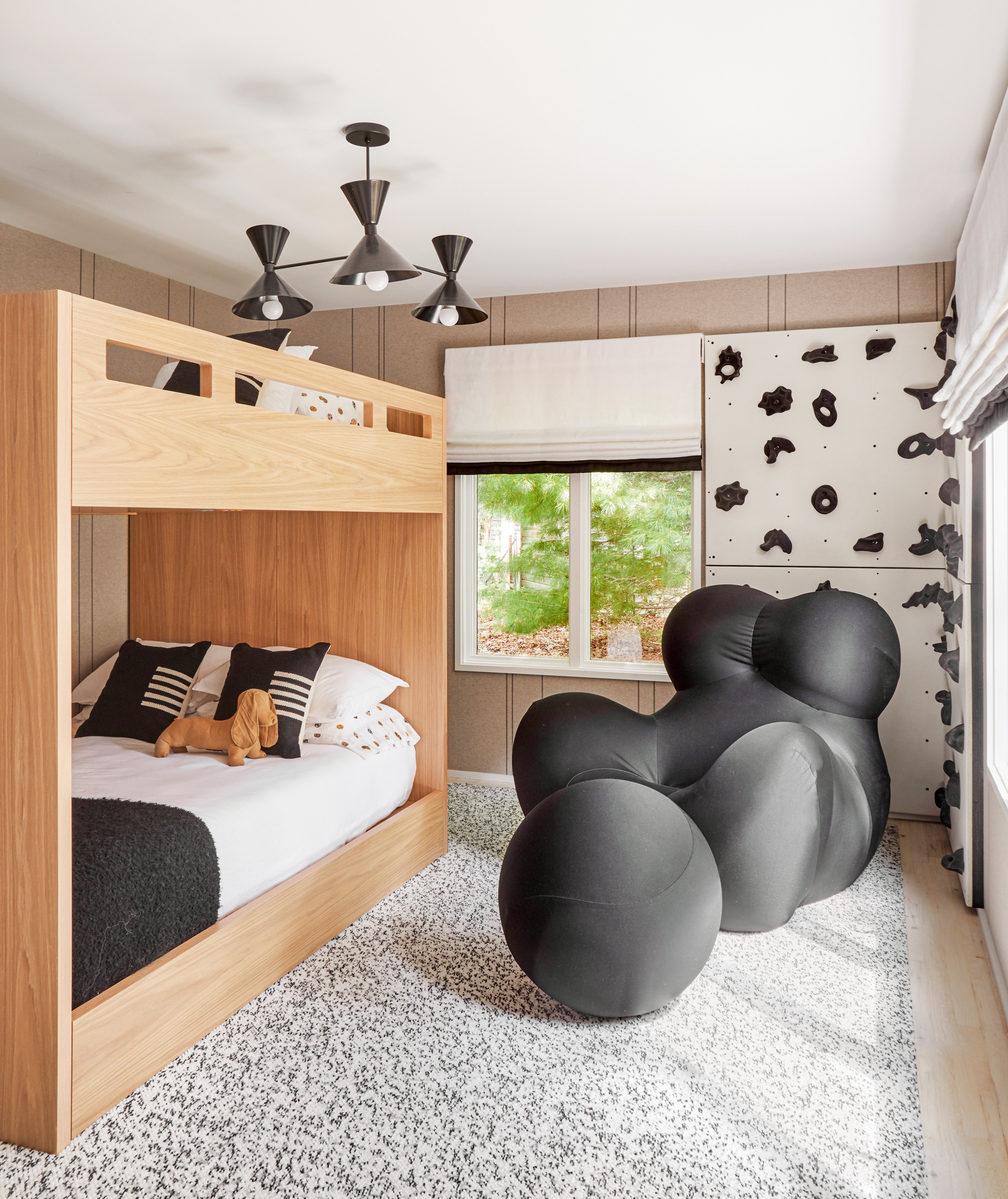 Children's room with wooden bunk bed, black armchair and footrest