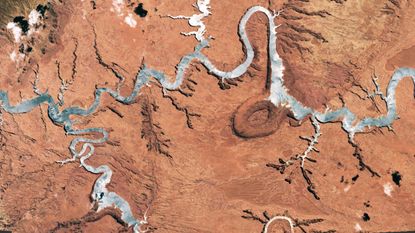 A satellite photo showing a giant river-like reservoir that has been turned silver by a sunglint 