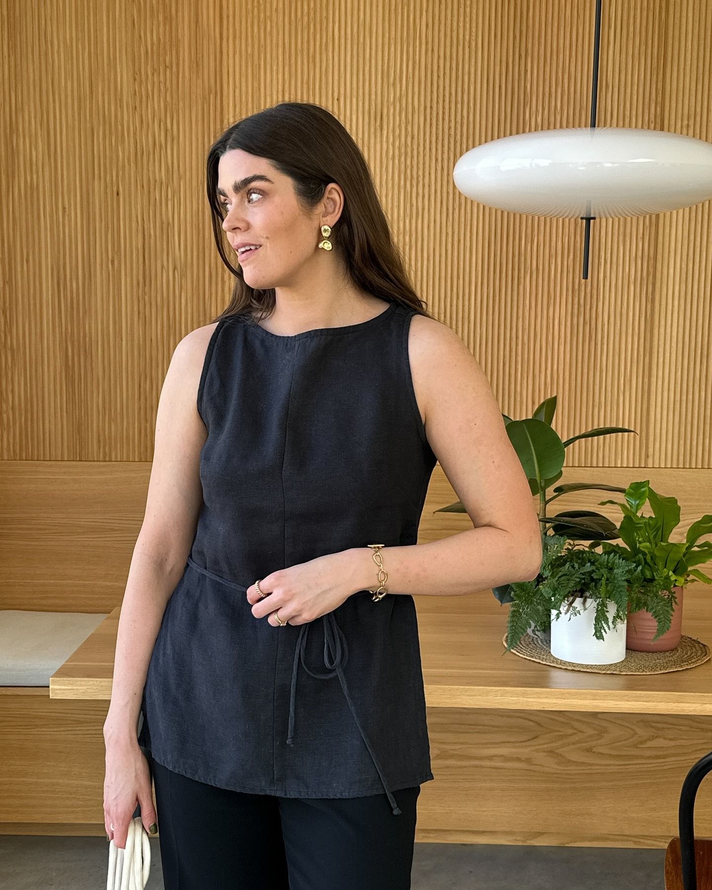 A woman wearing a linen boatneck blouse and black trousers.
