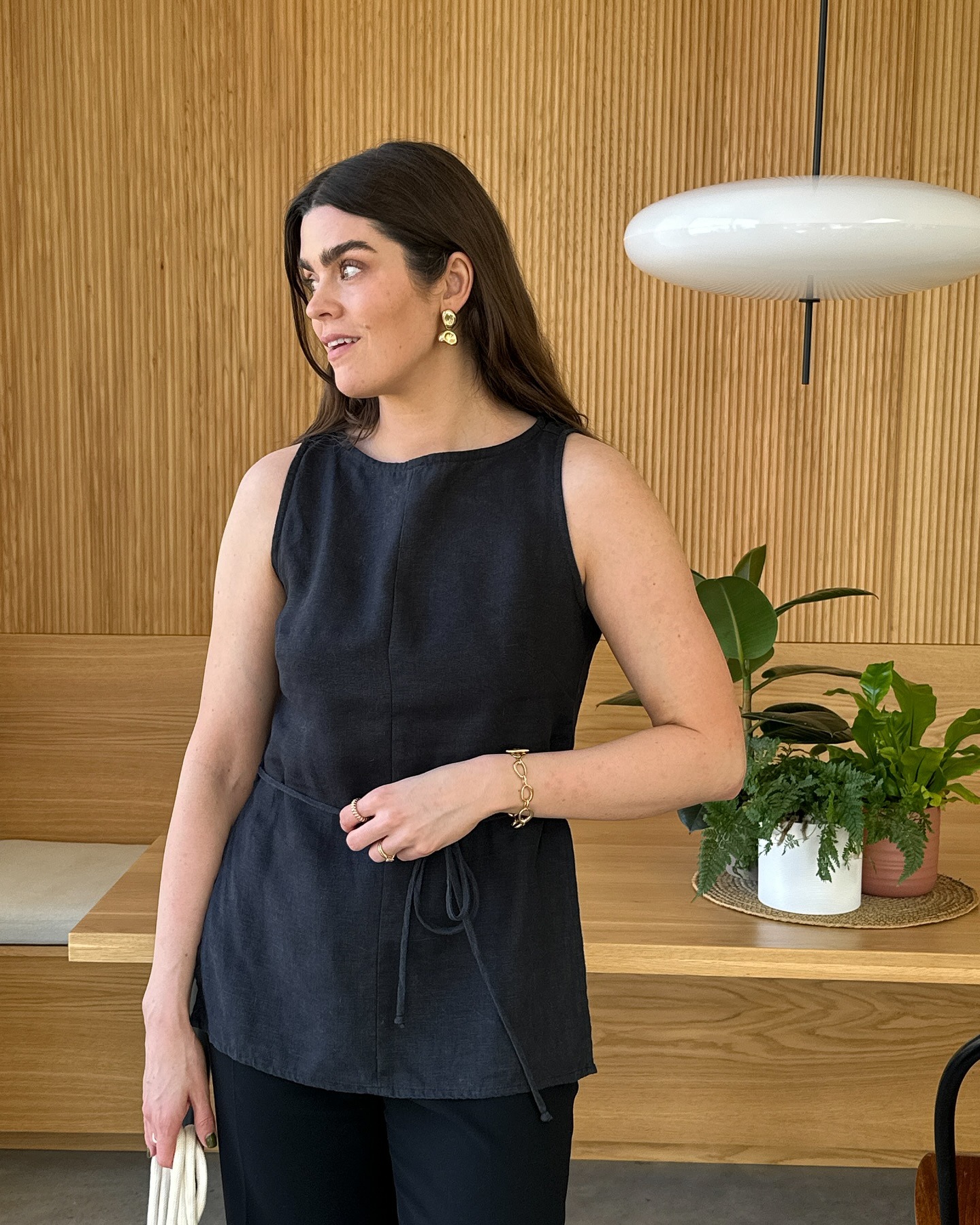 A woman wearing a linen boatneck blouse and black trousers.